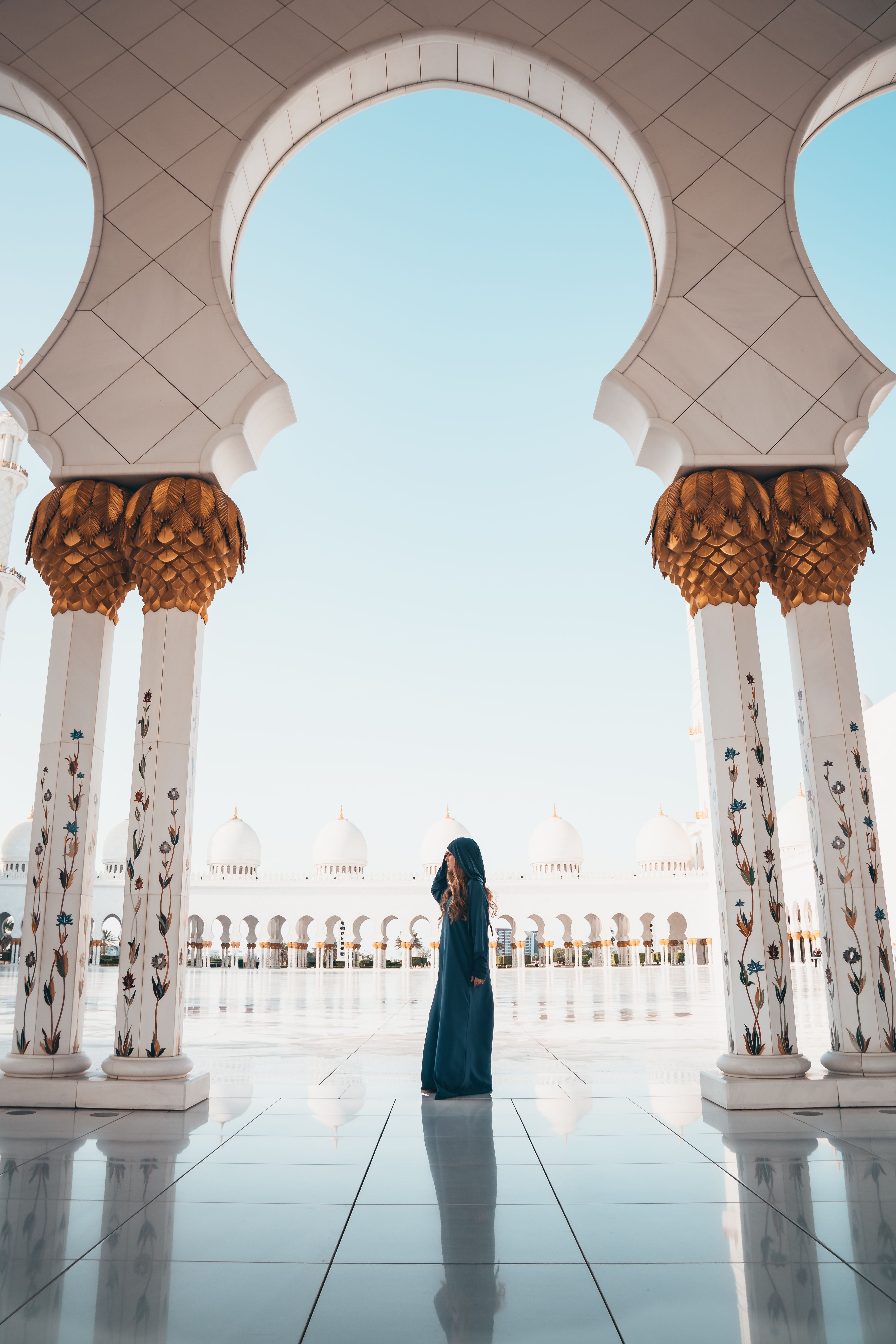 A visitor framed by ornate Abu Dhabi mosque arches representing architecture and culture.