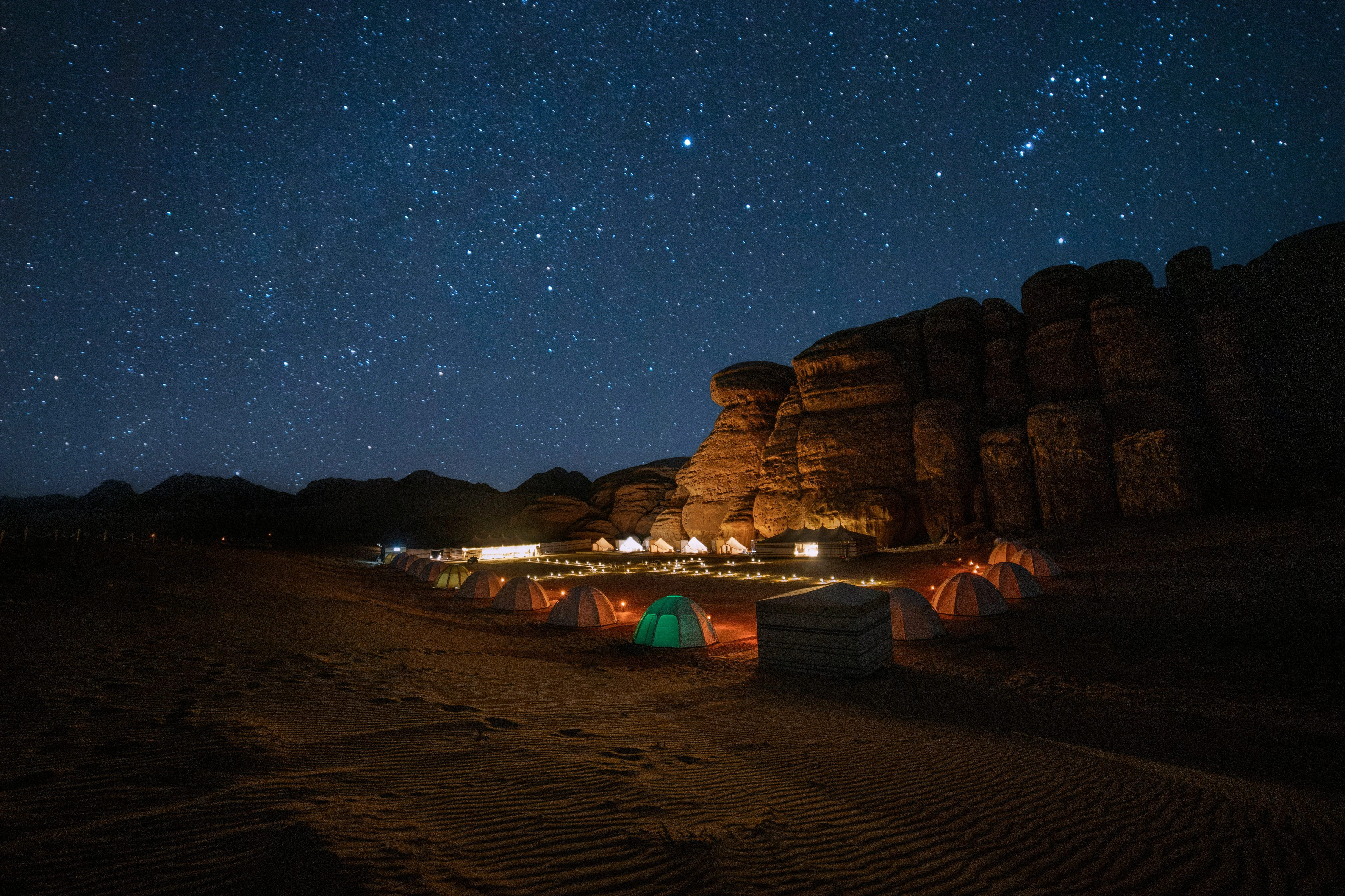 A lantern-lit desert camp beneath a star-filled night sky during an overnight desert safari.