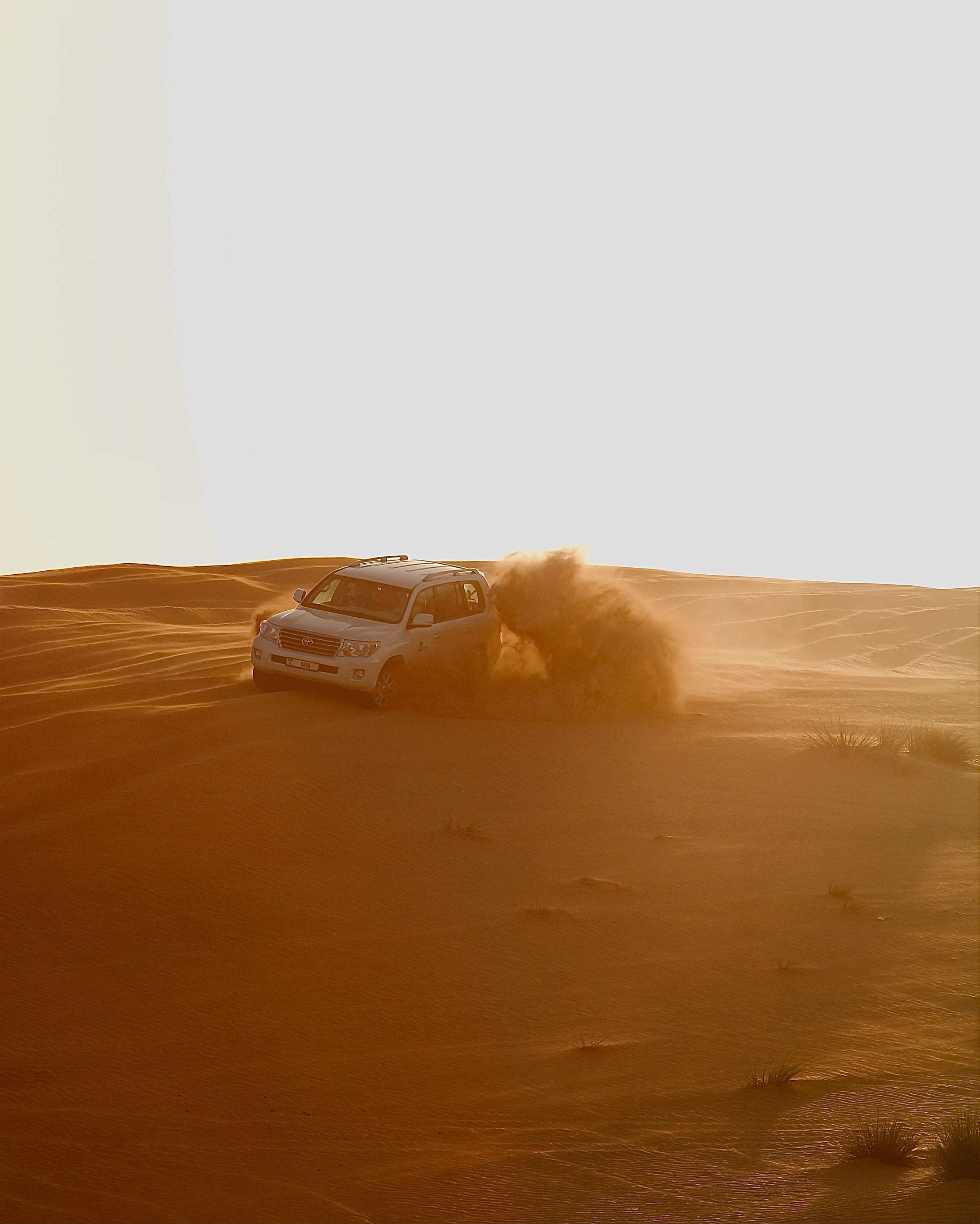 A four-wheel-drive vehicle carving through golden desert dunes during a UAE desert adventure.