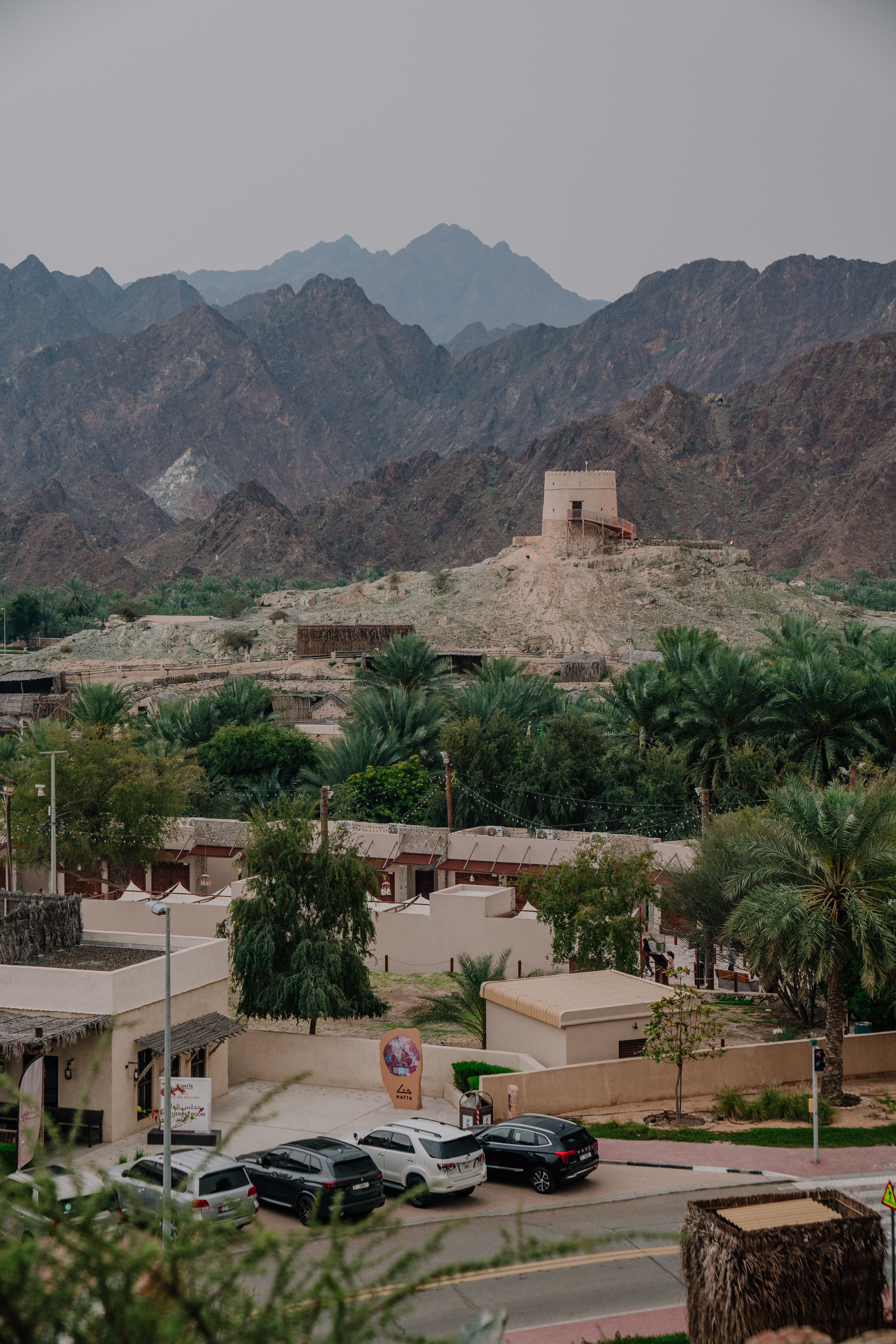 A Fujairah landscape with mountains, greenery, and heritage architecture.
