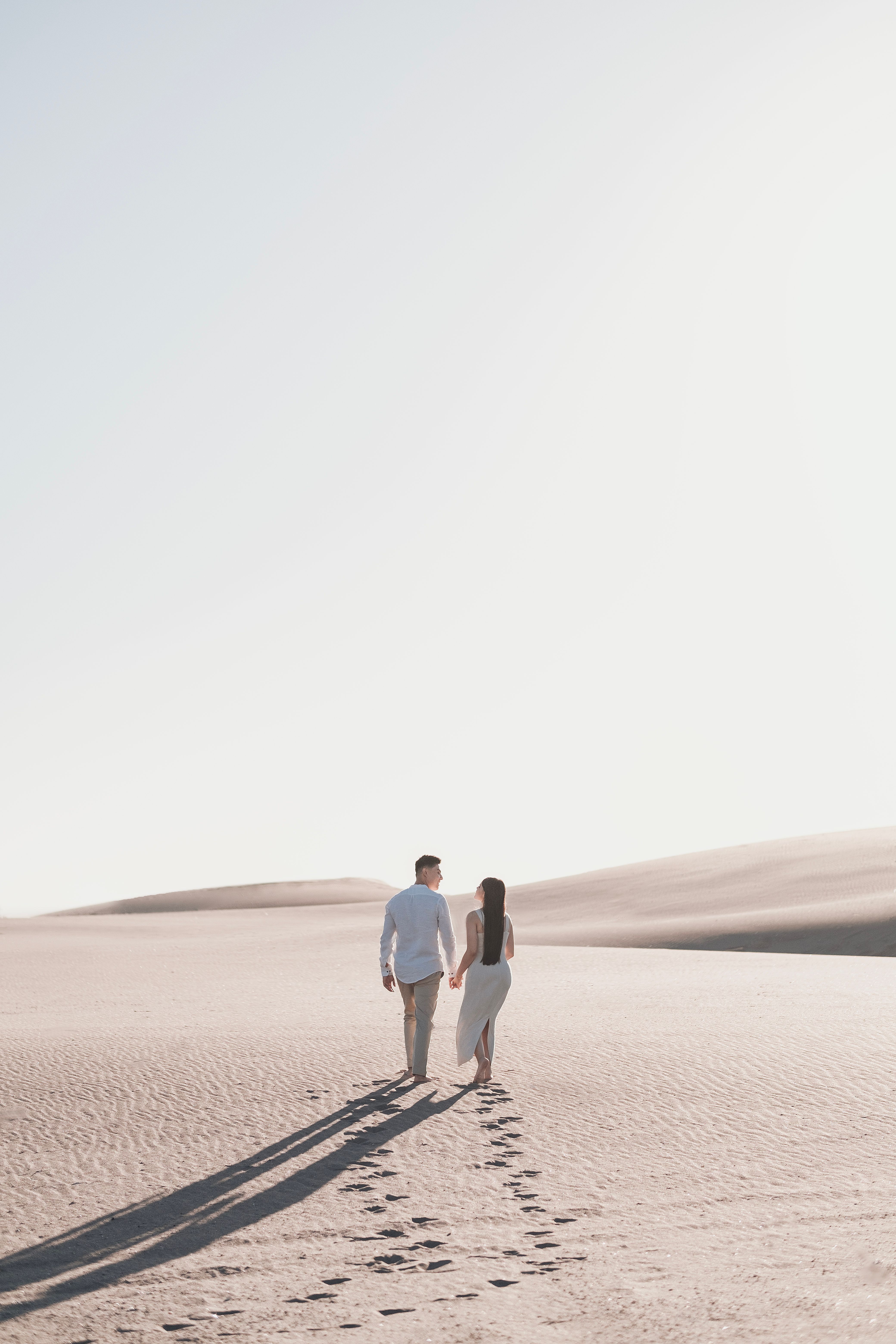 A couple walking across bright desert sands to represent luxury and private UAE experiences.