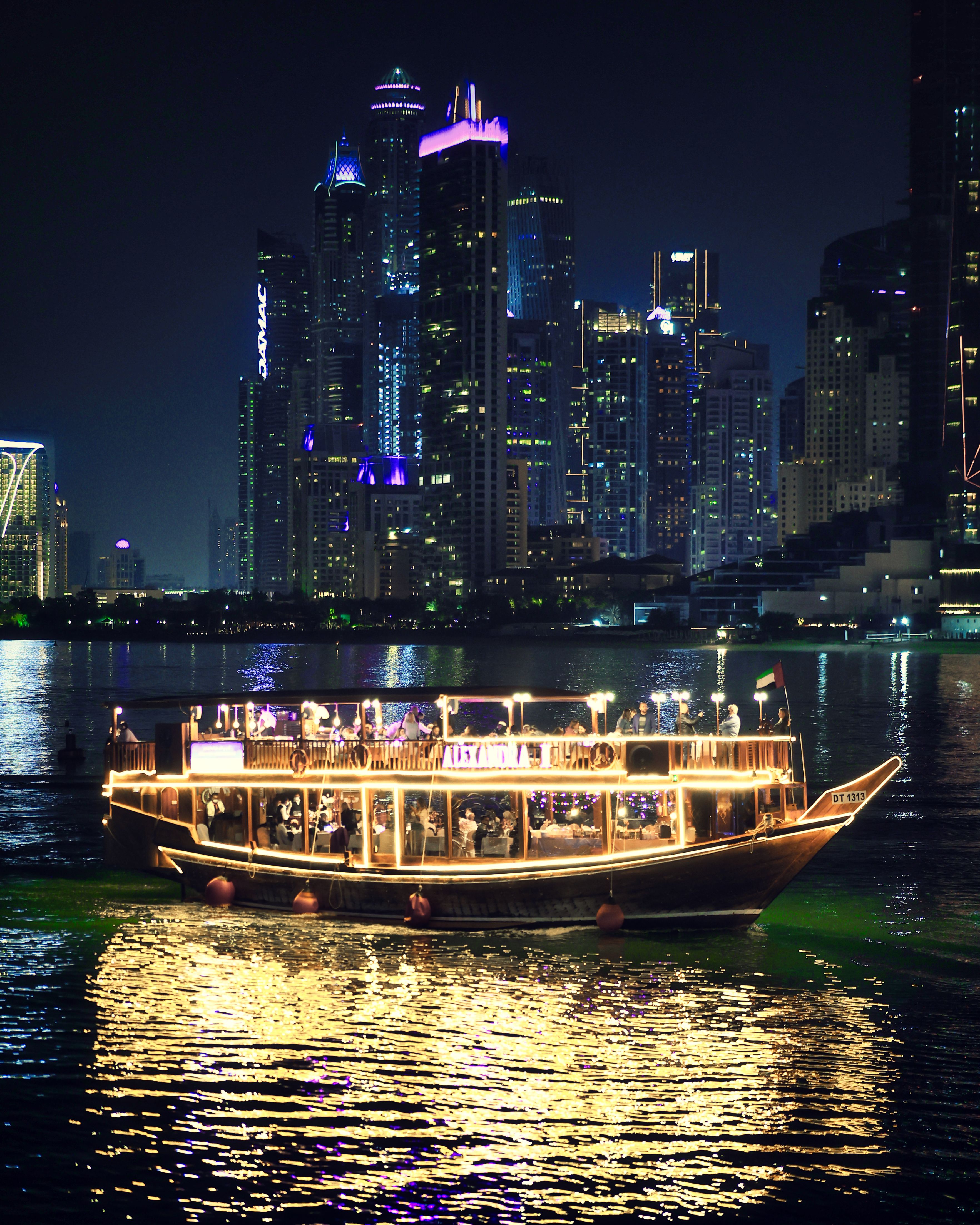 An illuminated dhow cruise on the water with a skyline backdrop representing UAE water experiences.