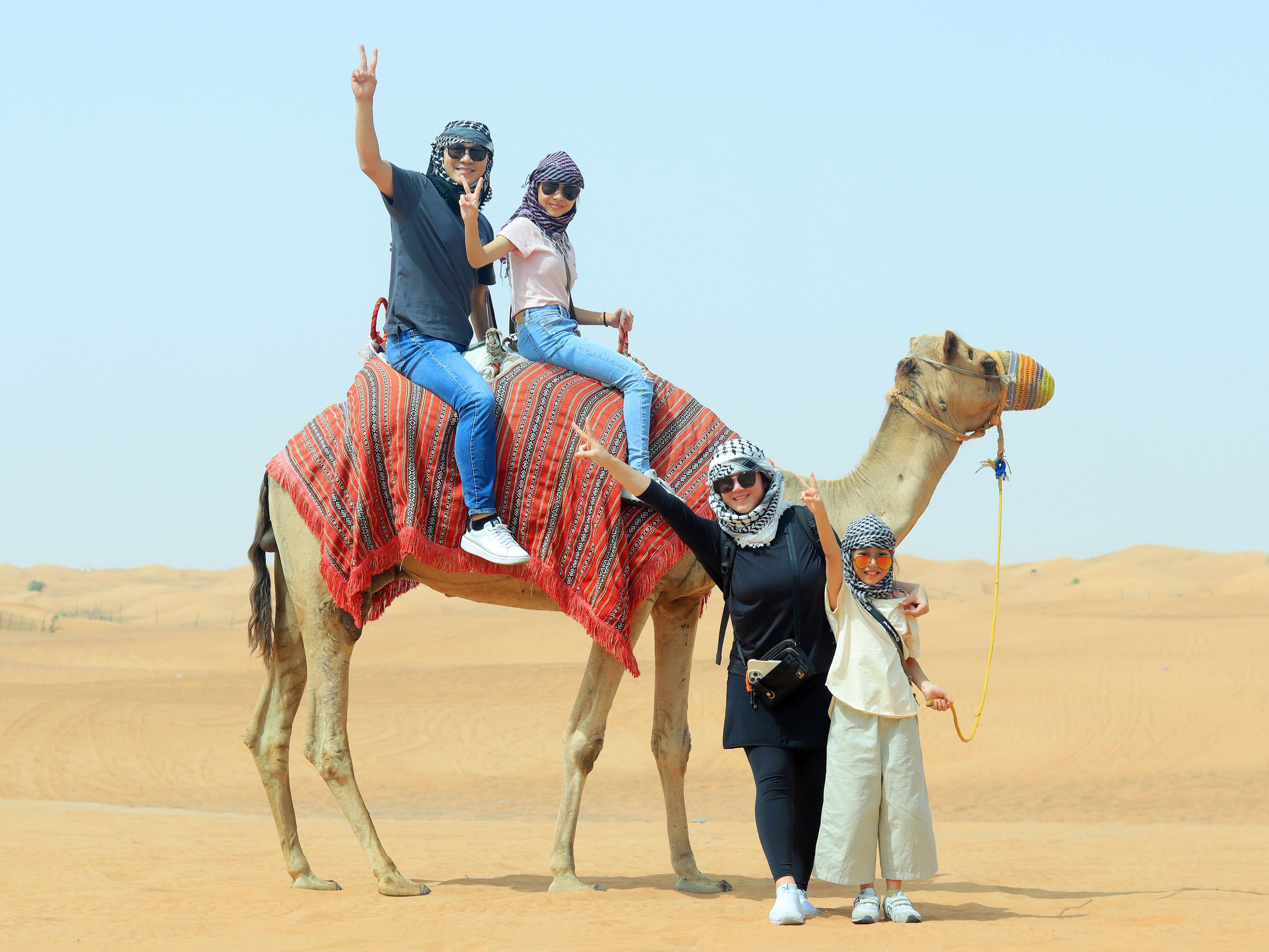 A family enjoying camel riding in the desert, representing welcoming and memorable travel with ARVY.